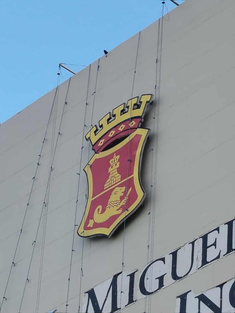 Building signage with large crest, MIGUEL partial text, outdoor, Metro Manila, sign maker Philippines by M&G Global Ads.