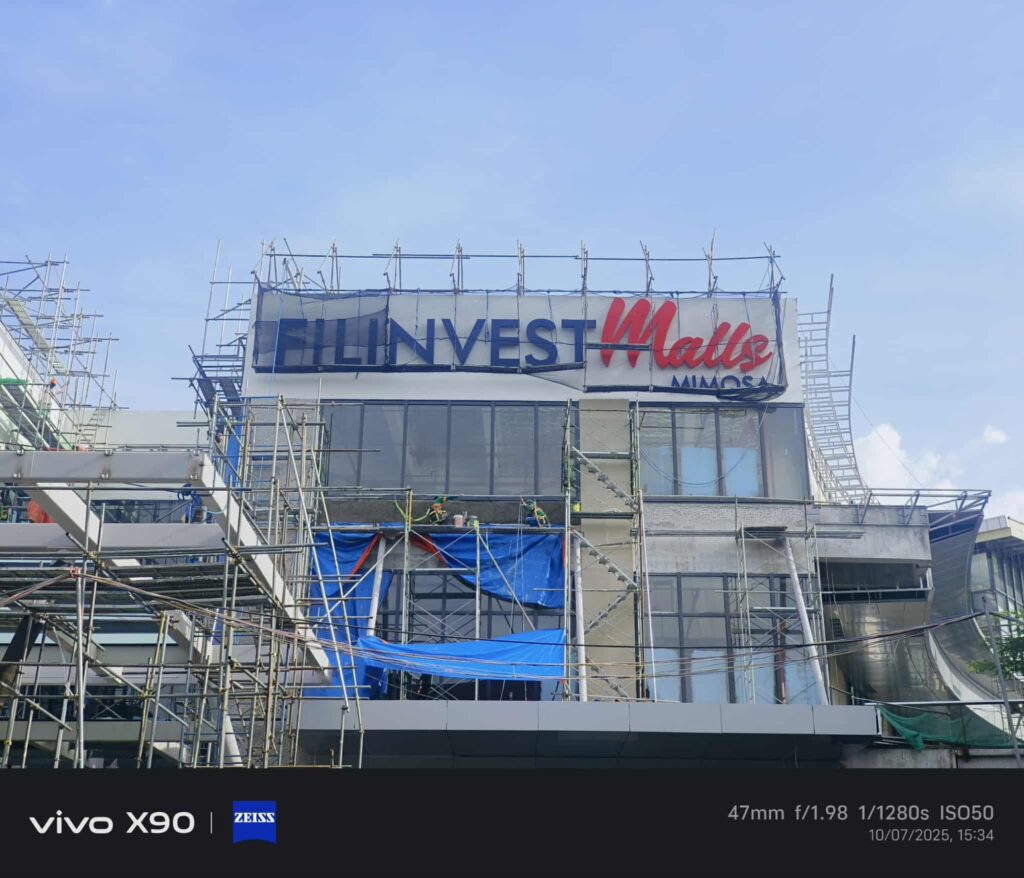 Building under construction with outdoor acrylic FILINVEST Malls signage, Metro Manila. Sign maker Philippines by M&G Global Ads.