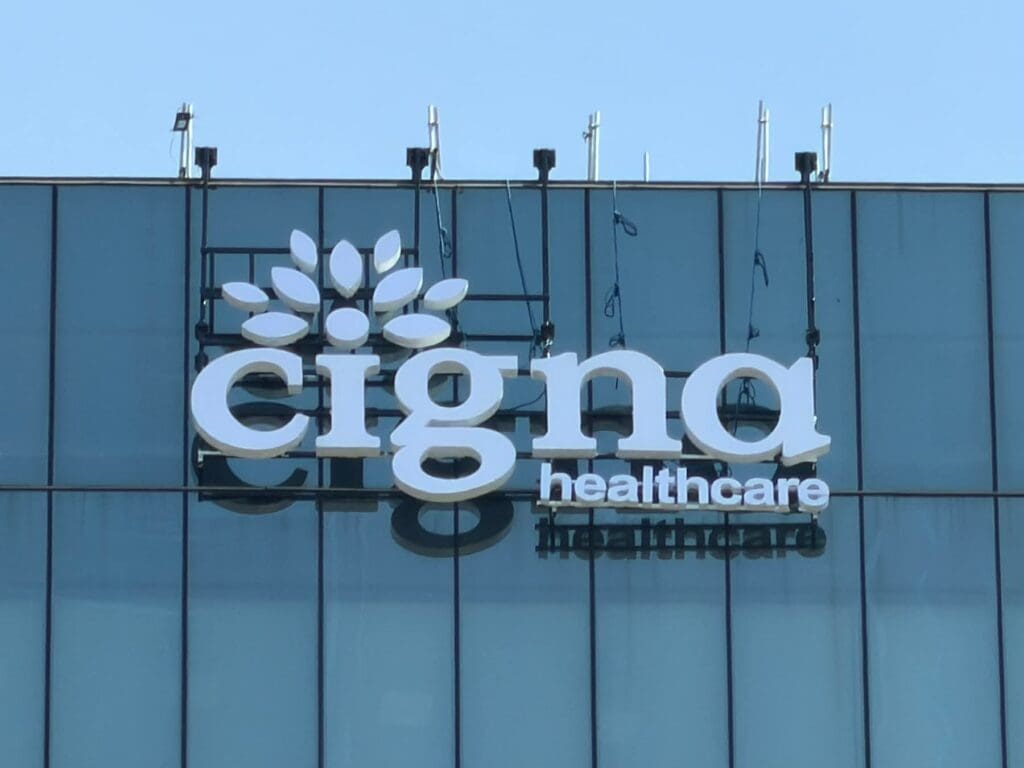 Cigna Healthcare building signage acrylic logo on glass facade under blue sky, Metro Manila sign maker Philippines by M&G Global Ads.