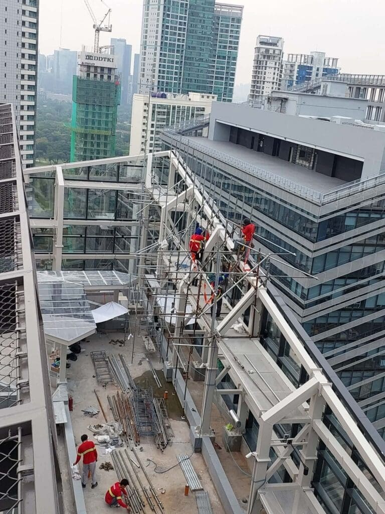 Construction workers installing building signage on steel structures atop a high-rise in Metro Manila by sign maker Philippines, M&G Global Ads.
