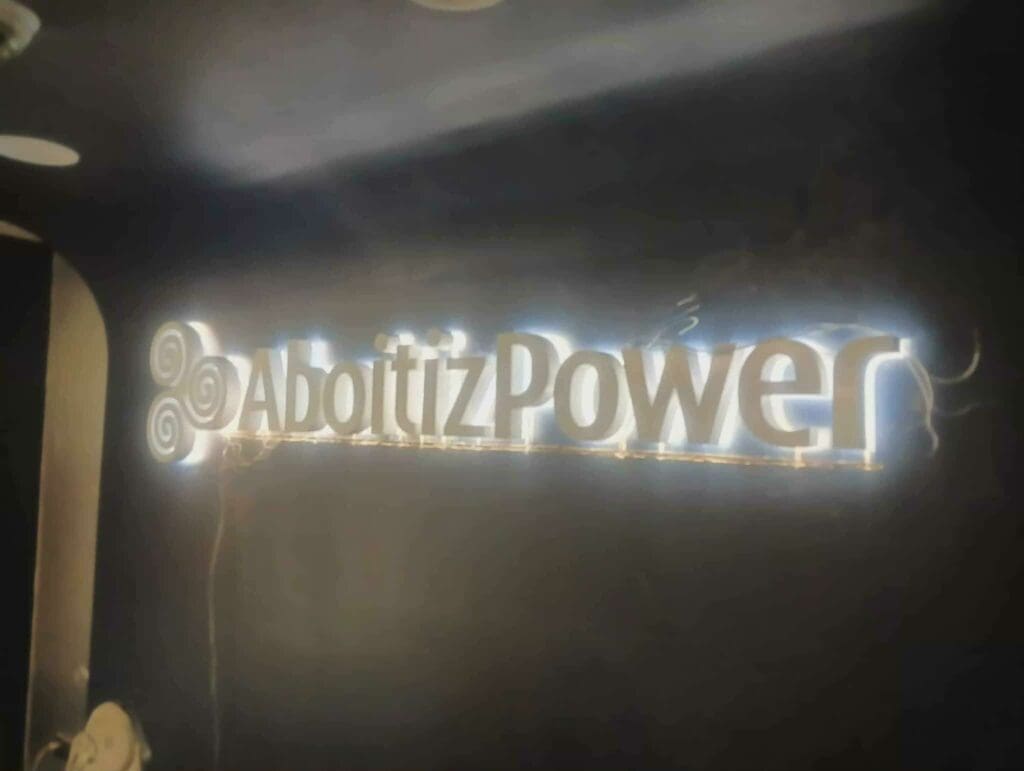 Illuminated acrylic LED AboitizPower logo signage with swirl design on dark wall in Philippines, sign maker Philippines by M&G Global Ads.