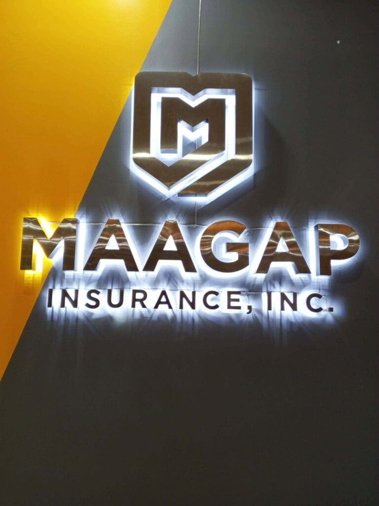 Illuminated acrylic signage with shield logo and MAAGAP INSURANCE, INC. text installed on a dark wall with a yellow diagonal stripe on the left, for MAAGAP INSURANCE, INC. in Metro Manila by sign maker Philippines, M&G Global Ads.
