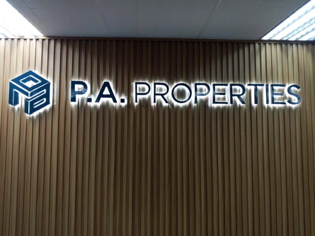 Indoor acrylic LED signage featuring a blue logo and the words "P.A. PROPERTIES" in white, uppercase letters, mounted on a wood-panel wall for P.A. Properties in the Philippines, sign maker Philippines by M&G Global Ads.