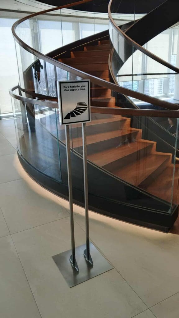 Indoor acrylic signage on metal stand with wellness quote in front of spiral staircase, Metro Manila, sign maker Philippines by M&G Global Ads.