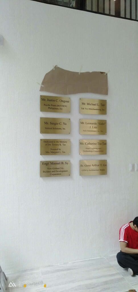 Indoor brass plaque signage with engraved names, partial brown paper cover, Metro Manila sign maker Philippines by M&G Global Ads.