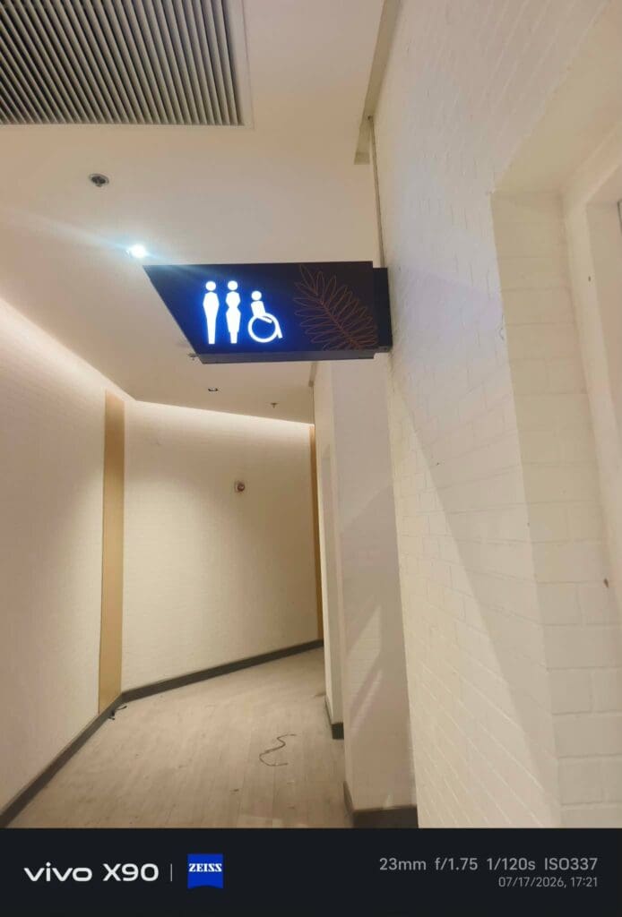 Indoor wayfinding restroom signage for men, women, and people with disabilities mounted on a white brick wall under a ceiling vent in Metro Manila, sign maker Philippines by M&G Global Ads.