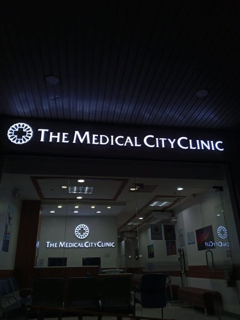 LED acrylic building signage for The Medical City Clinic above the entrance, featuring glass doors and a visible waiting area with chairs inside the clinic, Metro Manila, sign maker Philippines by M&G Global Ads.