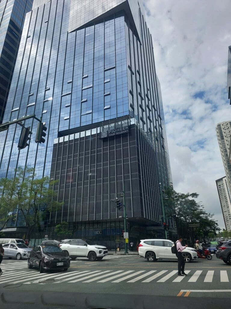 Modern glass office building with wayfinding and pylon signage at Metro Manila intersection, sign maker Philippines by M&G Global Ads.