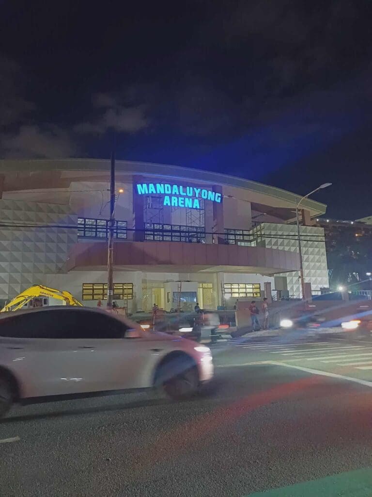 Night view of Mandaluyong Arena with blue outdoor LED building signage, cars in front—sign maker Philippines by M&G Global Ads.