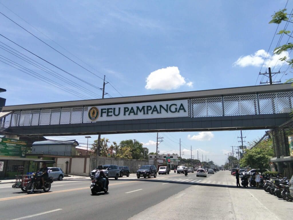 Outdoor acrylic building signage for FEU Pampanga on pedestrian overpass, busy road, Philippines, sign maker Philippines by M&G Global Ads.
