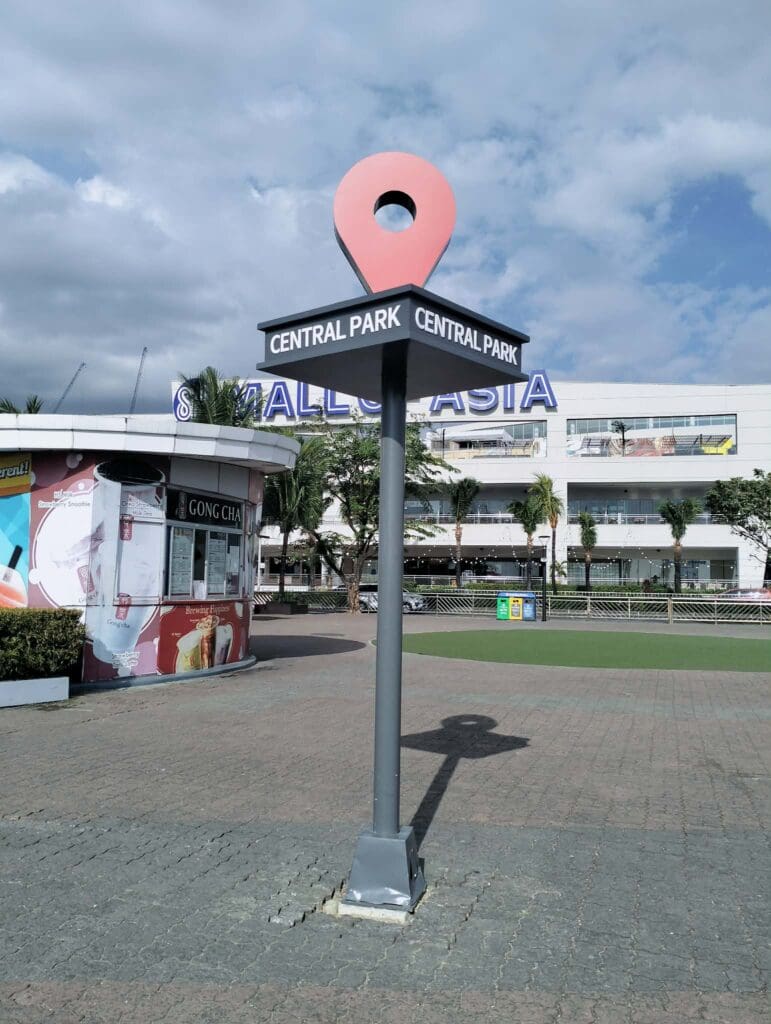 Outdoor acrylic wayfinding signpost for Central Park with red map pin icon near SM Mall of Asia, Metro Manila by sign maker Philippines by M&G Global Ads.