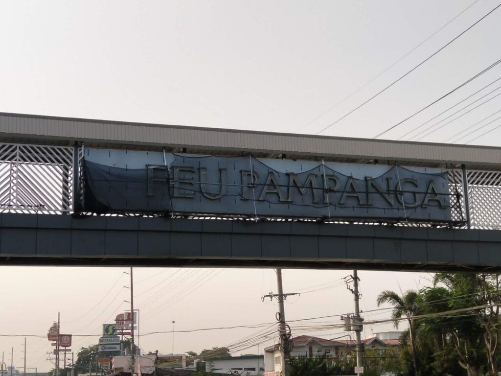 Outdoor building signage, faded acrylic “DEU PAMPANGA” sign on pedestrian overpass Pampanga, sign maker Philippines by M&G Global Ads.