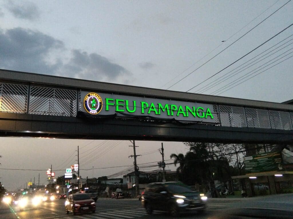 Outdoor LED acrylic signage for FEU Pampanga on a footbridge, busy road, Philippines, sign maker Philippines by M&G Global Ads.