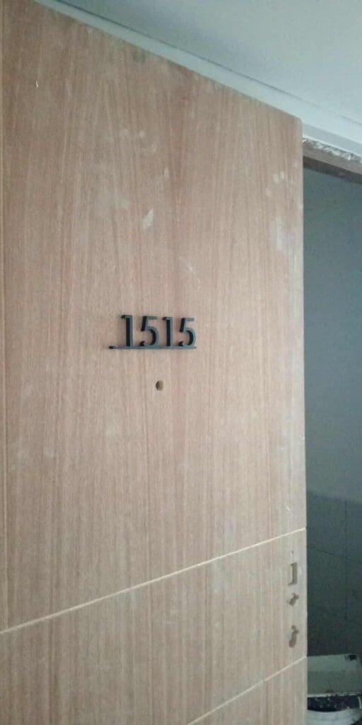 Room signage with black acrylic numbers "1515" on unfinished wooden door, Metro Manila, sign maker Philippines by M&G Global Ads.