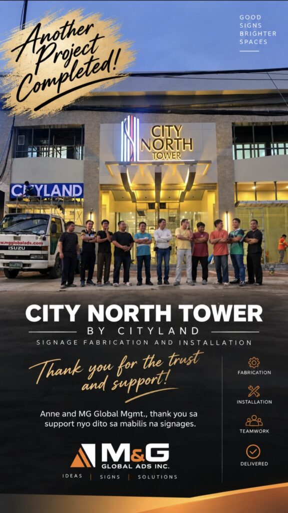A group of people stands in front of the brightly lit entrance of City North Towers at night, celebrating the completion of building signage fabrication and installation for City North Towers in Metro Manila. Project and company details are displayed in text. Building signage by sign maker Philippines by M&G Global Ads.