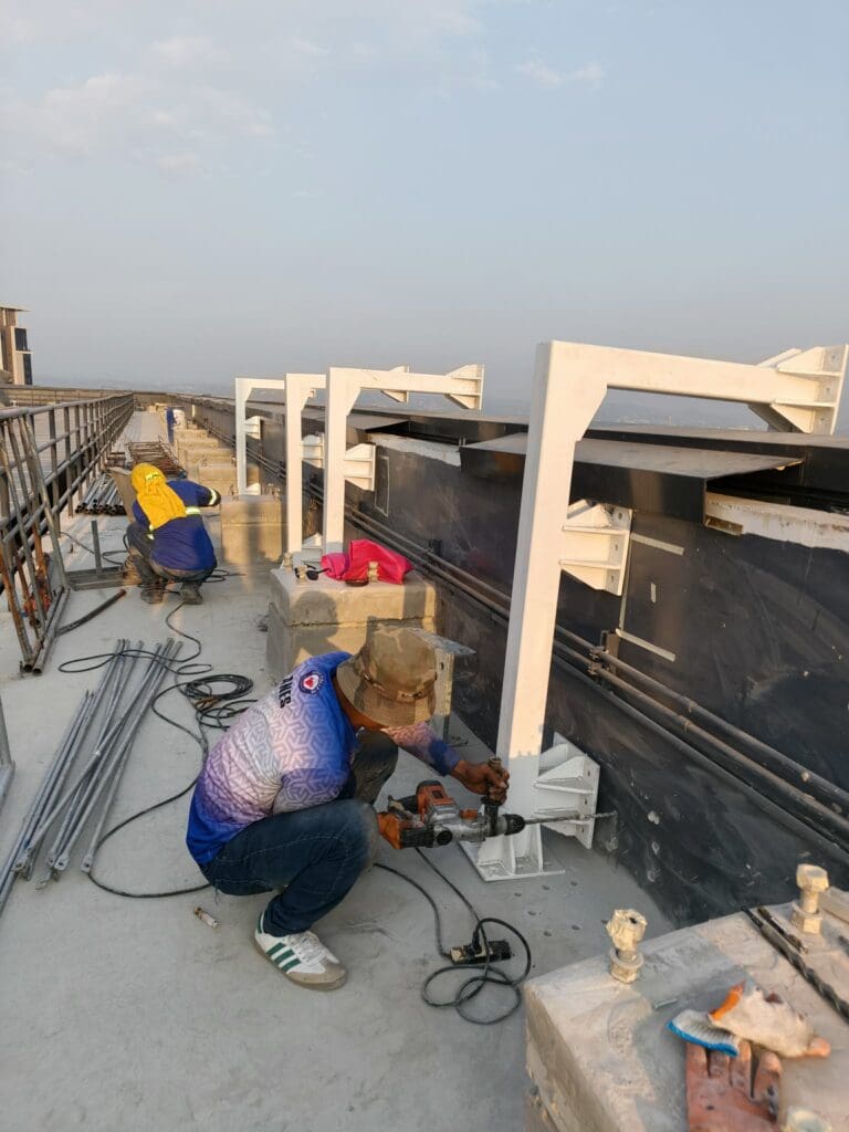 Sign maker Philippines installation of outdoor stainless steel building signage by construction workers on Metro Manila rooftop by M&G Global Ads.