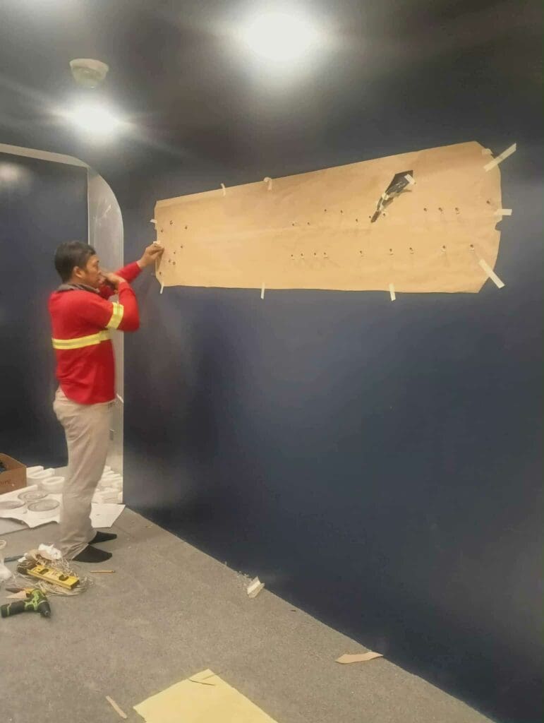 Sign maker Philippines installing acrylic indoor wall signage, dark blue wall, masking paper prep. Metro Manila by M&G Global Ads.