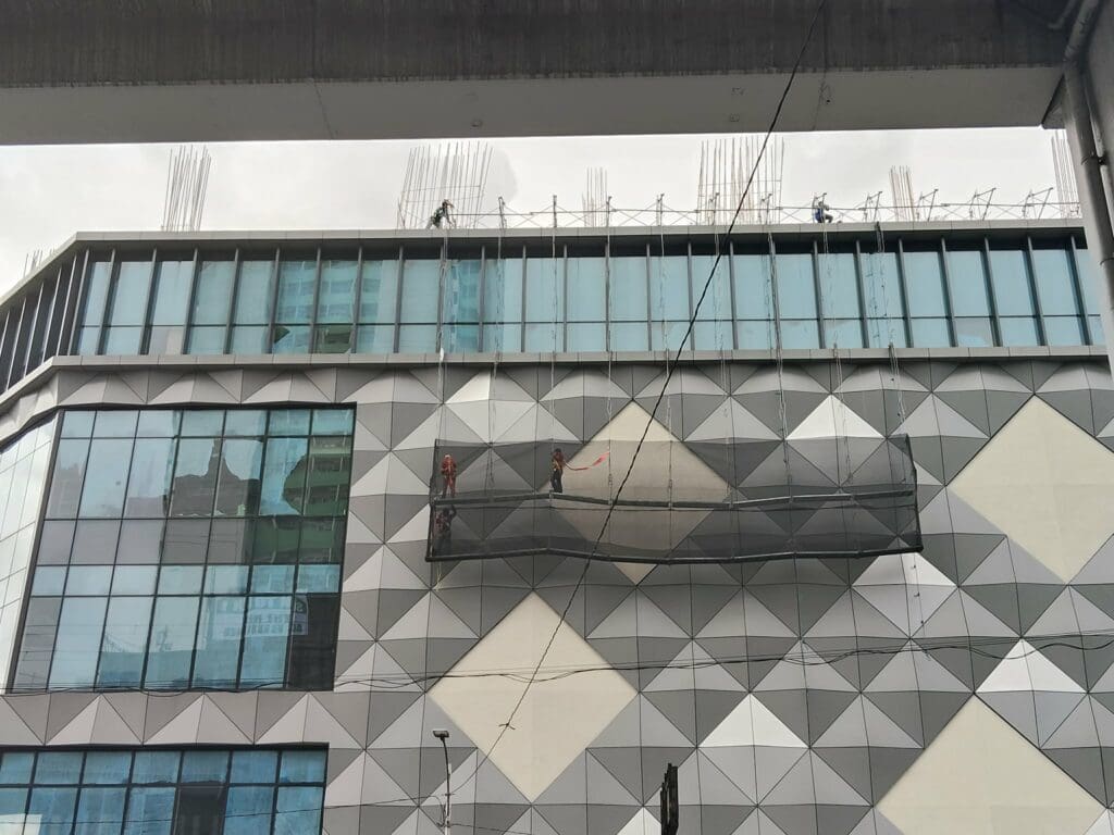 Sign maker Philippines installing building signage on modern facade with glass windows in Metro Manila by M&G Global Ads.