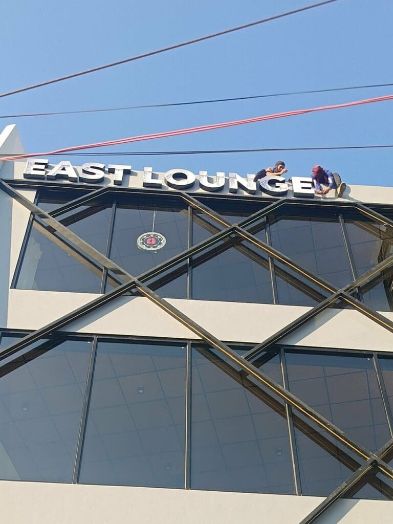 Sign maker Philippines installing outdoor acrylic building signage “EAST LOUNGE” on modern rooftop, Metro Manila by M&G Global Ads.