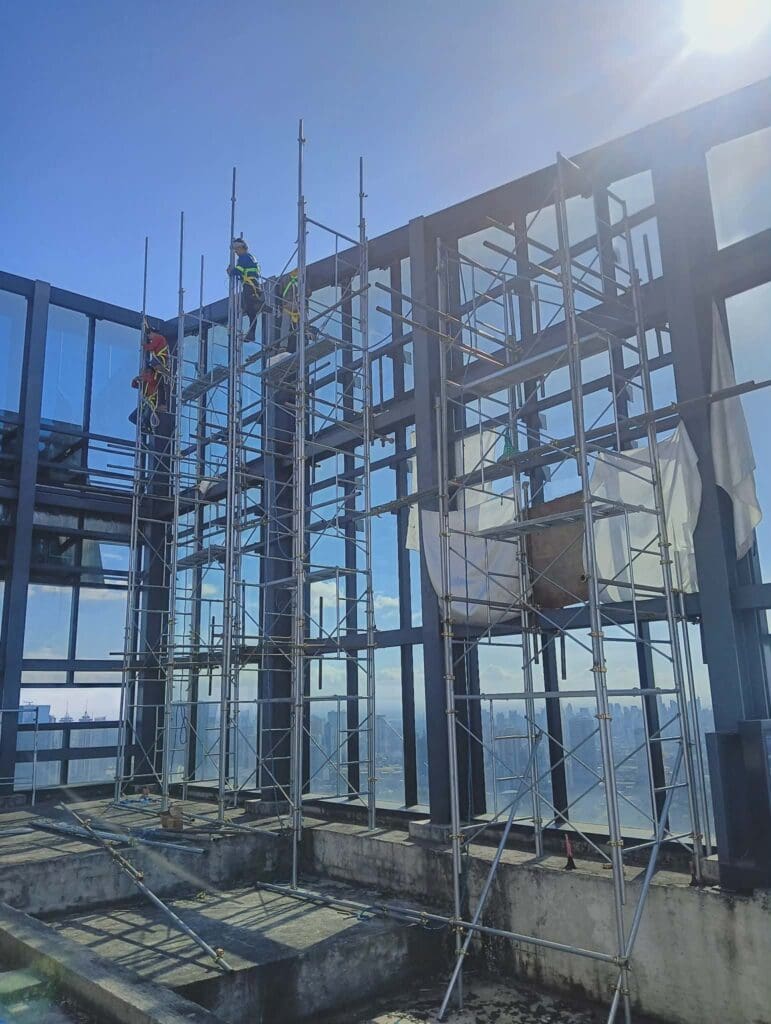 Sign maker Philippines installing outdoor building signage on glass facade under construction, Metro Manila, by M&G Global Ads.