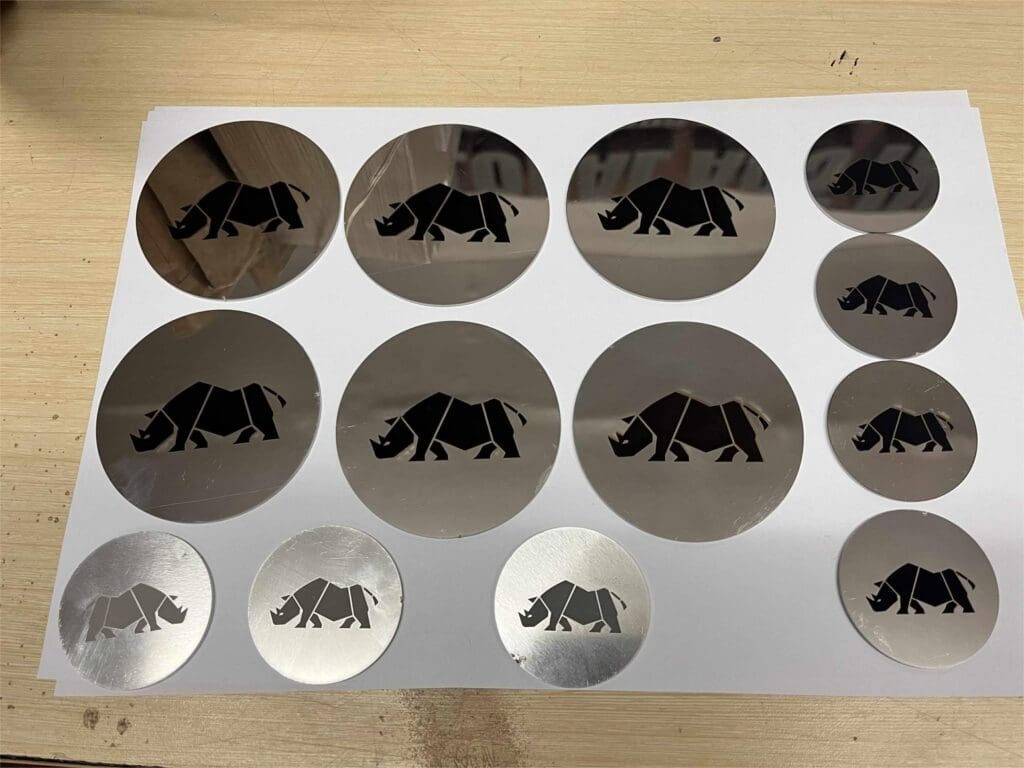 Stainless steel engraved signage discs with black rhino cut-out, displayed on wood, sign maker Philippines by M&G Global Ads.
