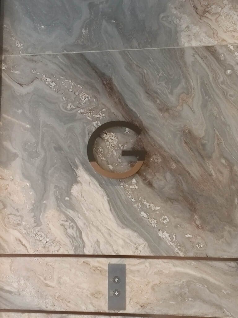Stainless steel letter G signage on marble wall, metallic plate and buttons, Metro Manila sign maker Philippines by M&G Global Ads.