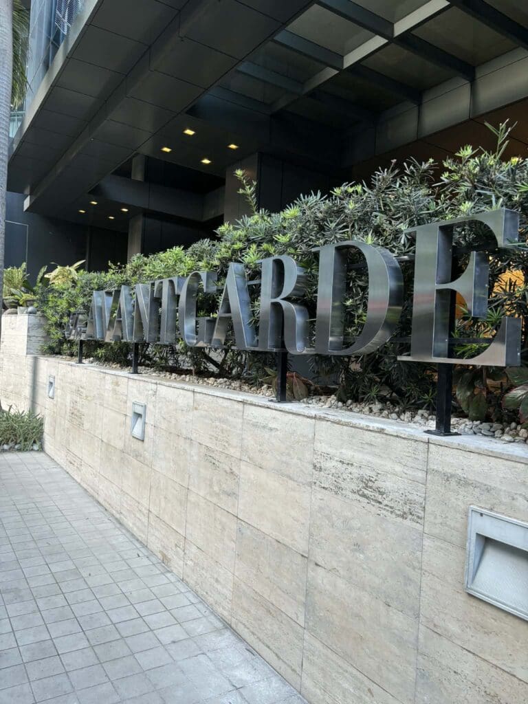 Stainless steel outdoor building signage AVANTGARDE on stone wall, modern facade, Metro Manila sign maker Philippines by M&G Global Ads.