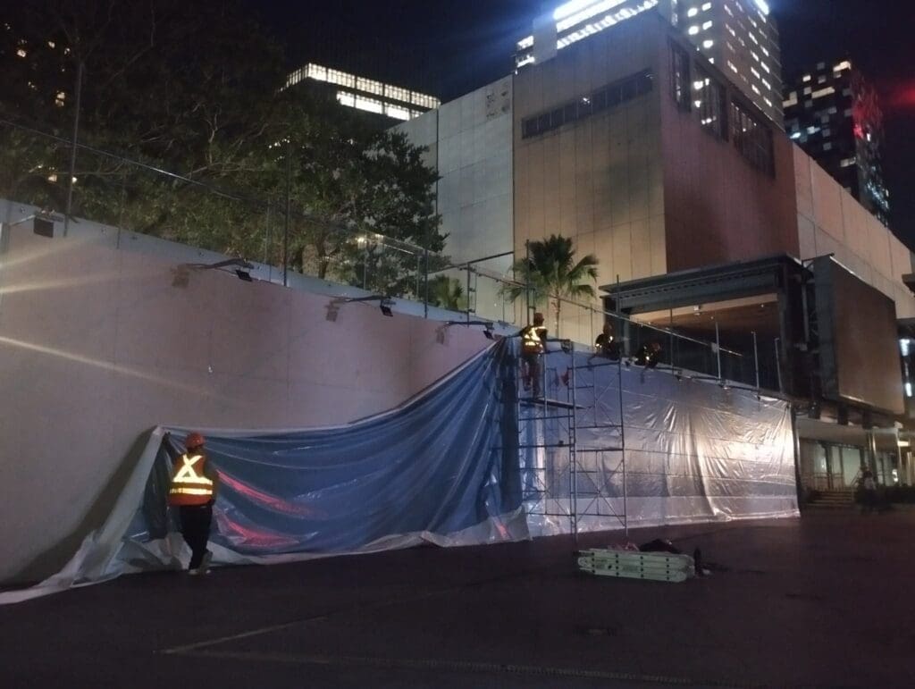 Two workers at night install outdoor building signage on scaffolding in Metro Manila, sign maker Philippines by M&G Global Ads.