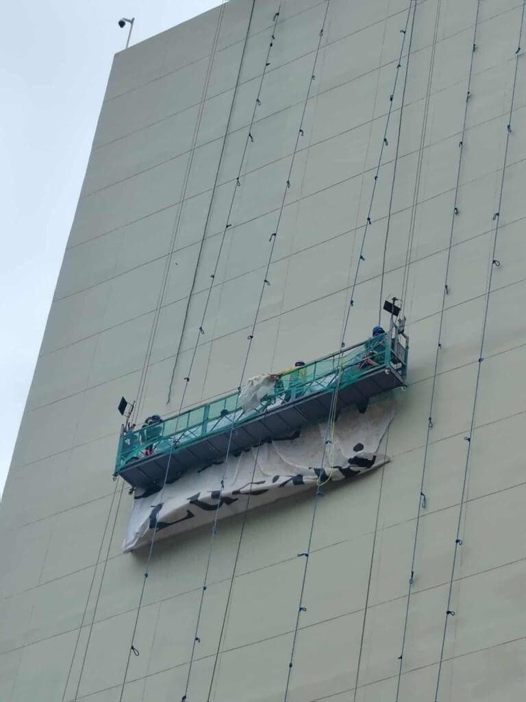 Two workers install building banner signage on high-rise, black and white print, Metro Manila, sign maker Philippines by M&G Global Ads.