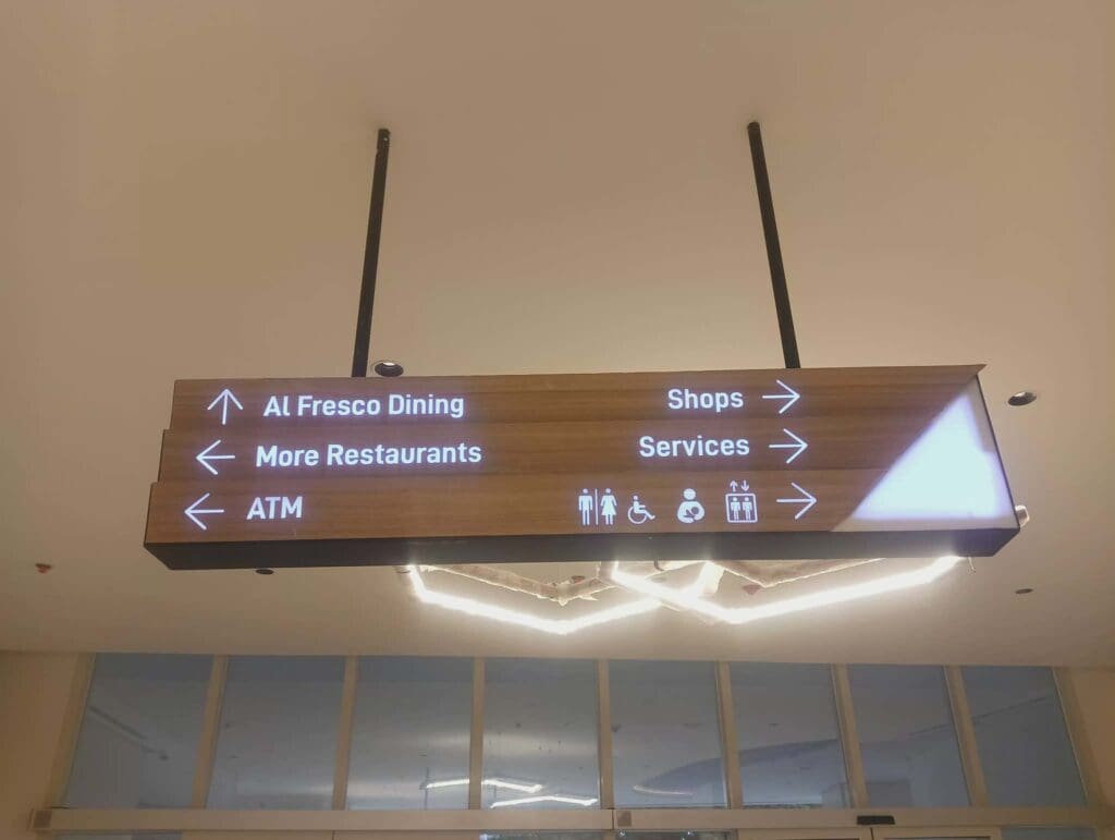 Wooden wayfinding ceiling sign with white text/icons for dining, ATM, shops in Metro Manila by sign maker Philippines M&G Global Ads.
