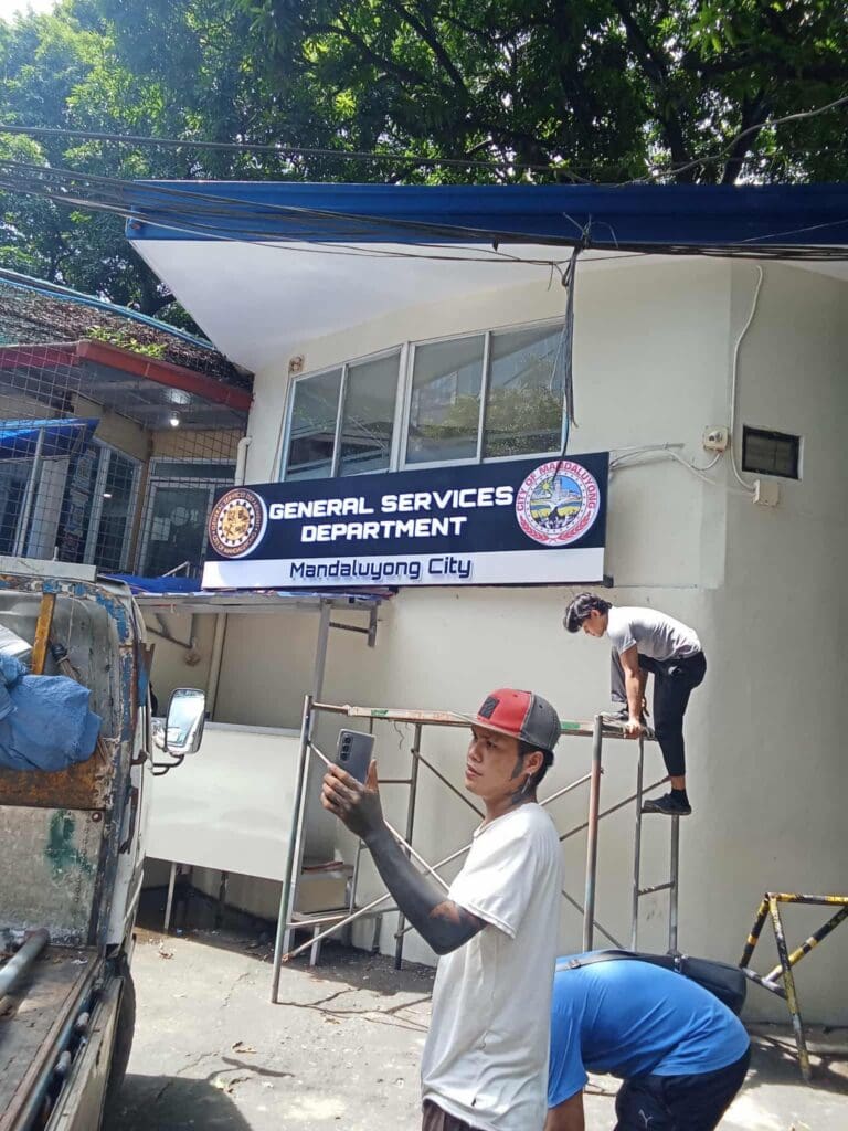 Workers install an acrylic building signage for General Services Department, Mandaluyong City. Sign maker Philippines by M&G Global Ads.