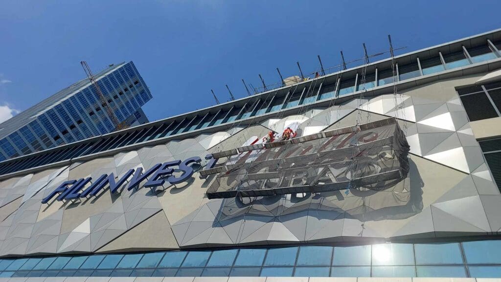 Workers install an outdoor building acrylic sign on a modern facade in Metro Manila, sign maker Philippines by M&G Global Ads.