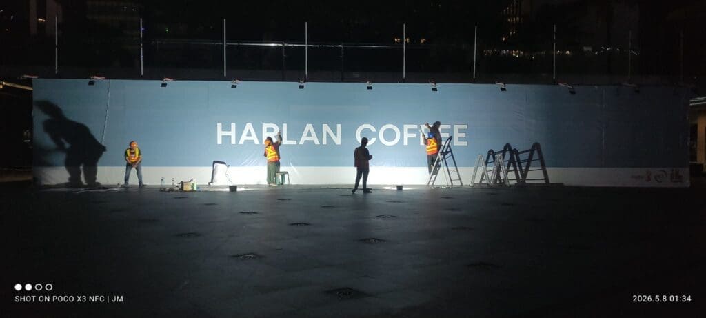 Workers install outdoor building signage for HARLAN COFFEE on blue wall, Metro Manila, sign maker Philippines by M&G Global Ads.