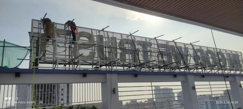 Workers on scaffolding install large rooftop building letters, outdoor signage Metro Manila by sign maker Philippines, M&G Global Ads.